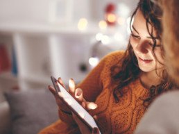 A tween girl uses a tablet while sitting on the couch.