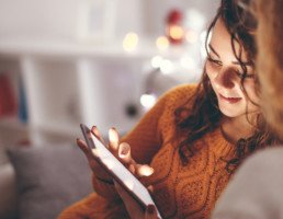 A tween girl uses a tablet while sitting on the couch.