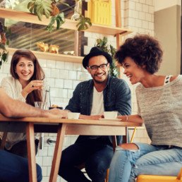 Cheerful young friends having fun while talking in a cafe. Group of young people meeting in a cafe.