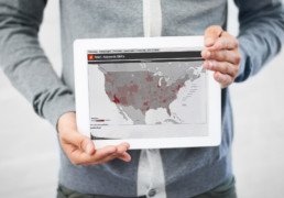 A man holding a tablet that displays a map of the United States.